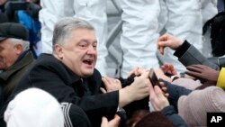 Ukrainian President Petro Poroshenko, left, greets people gathered to support an independent Ukrainian church near the St. Sophia Cathedral in Kyiv, Ukraine, Saturday, Dec. 15, 2018. 