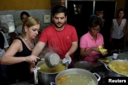 Diego Prada (C), Maria Luisa Pombo (L) and other volunteers of the Make The Difference (Haz La Diferencia) charity initiative prepare soup to be donated, at Maria Luisa's kitchen in Caracas, March12, 2017.