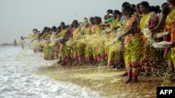 FILE - Indian women throw flowers into the sea as an offering during a ceremony for the victims of the 2004 tsunami at Marina Beach in Chennai, Dec. 26, 2016.