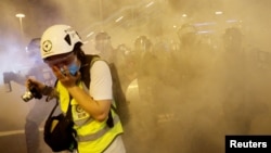 在香港警察向反送中示威者发射催泪弹后一名记者用手掩住口鼻。（2019年8月4日）