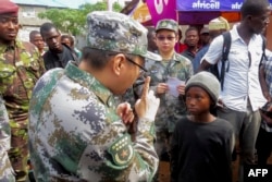 FILE - A medical team from the Chinese People’s Liberation Army meets with locals in Sierra Leone as they arrive close to the site of a mudslide on Sugar Loaf Mountain, in Freetown, Aug. 17, 2017.
