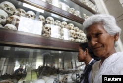 FILE - A woman cries in front of the skulls and bones of more than 8,000 victims of the Khmer Rouge regime during a Buddhist ceremony at Choeung Ek, a "Killing Fields" site located on the outskirts of Phnom Penh, Cambodia, April 17, 2015.