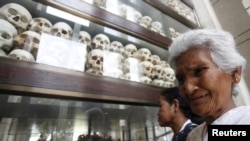 FILE - A woman cries in front of skulls and bones of more than 8,000 victims of the Khmer Rouge regime at a "Killing Fields" site on the outskirts of Phnom Penh, Cambodia, April 17, 2015.