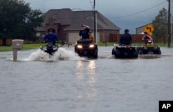 Kids ride an ATV in a street flooded by Tropical Storm Harvey, in the Clearfield Farm subdivision in Lake Charles, La., Aug. 29, 2017.