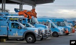 FILE - Pacific Gas & Electric vehicles are parked at the PG&E Oakland Service Center in Oakland, Calif., Jan. 14, 2019. The year's first fire danger warning in Northern California is putting Pacific Gas & Electric on alert. The utility said starting Saturday, it might turn off power to thousands of customers in areas north of San Francisco and in the Sierra foothills to help reduce the risk of fire.