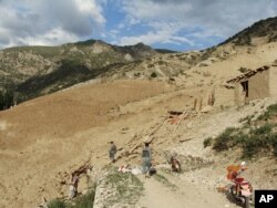 Polisi nasional Afghanistan berdiri di lokasi setelah gempa bumi melanda Provinsi Baghlan, utara Kabul, Afghanistan, Senin, 11 Juni 2012. (Foto: AFP)...