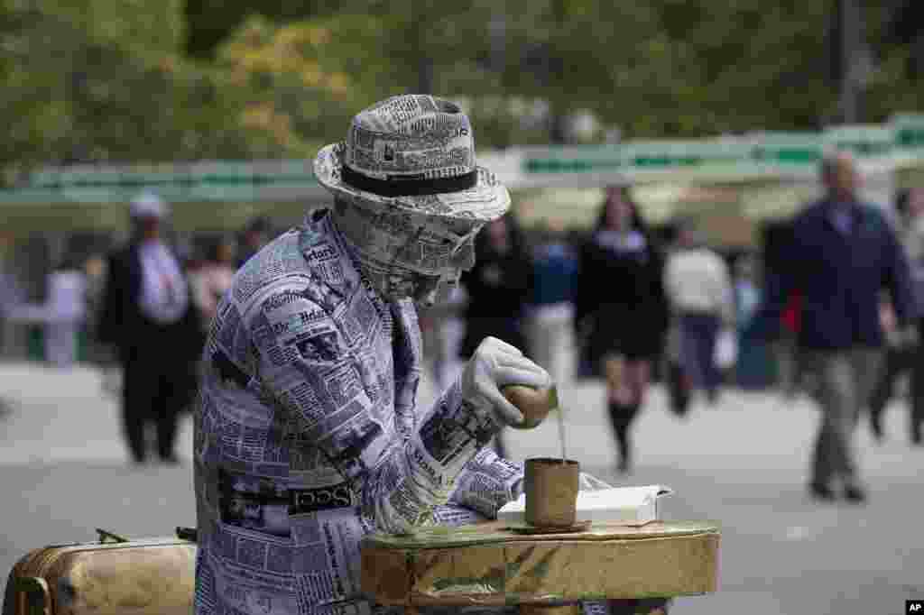 Seorang artis menutup dirinya dengan tempelan surat kabar sambil membaca buku pada hari pembukaan festival buku tahunan di Madrid, Spanyol. &nbsp;