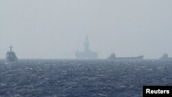 FILE - Ships and an oil rig, center, which China calls Haiyang Shiyou 981, and Vietnam refers to as Hai Duong 981, is seen in the South China Sea, off the shore of Vietnam, May 14, 2014.