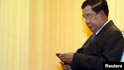 FILE - Cambodia's Prime Minister Hun Sen looks at his smartphone at a ceremony in Phnom Penh.