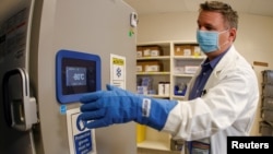 ARHIVA - Farmaceut u Los Anđelesu ispred specijalnog frižidera za čuvanje Fajzer vakcina na temperaturi od -80 stepeni Celzijusa (Foto: Reuters)