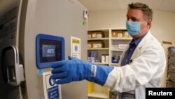 FILE - Pharmacy supervisor Kevin Weissman wears a thick glove as he opens the door of a special freezer that will hold the Pfizer vaccine at LAC USC Medical Center, during the outbreak of the coronavirus disease, in Los Angeles, California, Dec. 10. 2020.