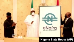 Nigerian President Muhammadu Buhari, center, and Central Bank governor Godwin Emefiele, right, launch the e-Naira digital currency in Abuja, Oct. 25, 2021.