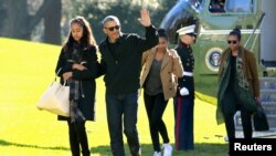 Tổng thống Mỹ Barack Obama vẫy chào khi ông đi cùng Đệ nhất Phu nhân Michelle Obama (phải) và hai người con gái của họ là Malia (trái) và Sasha trên Bãi Cỏ Nam Tòa Bạch Ốc, Washington, ngày 3 tháng 1, 2016. 