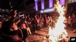 People gather around a bonfire before riot police use a water cannon to disperse protesters during a rally against a bill which would allow Turkey's authorities to block web pages for privacy violations without a prior court decision, in Istanbul, Feb. 22, 2014.