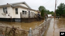 State police and firefighters search homes along flooded streets in Rainelle, W.Va., June 25, 2016.