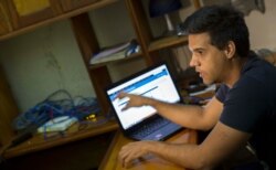 In this Jan. 4, 2015 photo, Rafael Antonio Broche Moreno talks during an interview with The Associated Press, next to his computer, modem and intranet network cabling in Havana. Disconnected from the real Internet, the intranet network is limited.