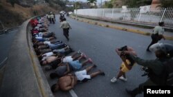 People detained by security forces lie on the street after looting broke out during an ongoing blackout in Caracas, Venezuela, March, 10, 2019.