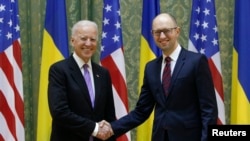 Wakil President Joe Biden berjabat tangan dengan Perdana Menteri Ukraina (kanan) Arseniy Yatsenyuk dalam pertemuan di Kyiv, November 2014.
