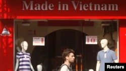 A tourist walks past a clothes shop in Hanoi.