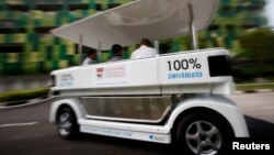 FILE - People ride on a driverless electric vehicle at the Nanyang Technological University (NTU) in Singapore.