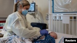 Seorang perawat merawat bayi berusia 3 bulan yang kesulitan bernafas akibat terkena COVID-19 di rumah sakit anak di Augusta, Georgia (15/1). 