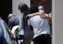 Friends and relatives of Archbishop Desmond Tutu console each other outside his home in Cape Town, South Africa, Dec. 26, 2021.