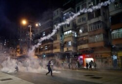 Protesters react to tear gas from Shum Shui Po police station in Hong Kong, Aug. 14, 2019.