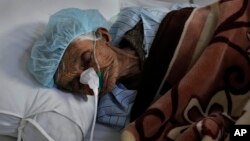 An Afghan patient infected with COVID-19 lies on a bed in the intensive care unit of the Afghan Japan Communicable Disease Hospital, in Kabul, Afghanistan, Monday, Feb. 7, 2022. 