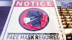 Tanda wajib mengenakan masker dipasang di depan sebuah toko di Philadelphia, 16 Februari 2022. (Ilustrasi). AS memperpanjang mandat penggunaan masker bagi penumpang pesawat dan pengguna angkutan umum.