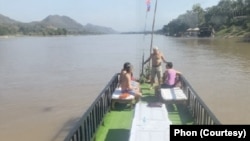 ນັກທ່ອງທ່ຽວທີ່ໃຊ້ບໍລິການ ພາກັນນັ່ງຫຼິ້ນຢູ່ທາງເບື້ອງຫົວເຮືອ.