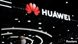 Seorang pengunjung berdiri di dekat logo Huawei yang terpasang pada Konferensi Kecerdasan Buatan Dunia di Shanghai, pada 1 September 2022. (Foto: Reuters/Aly Song)