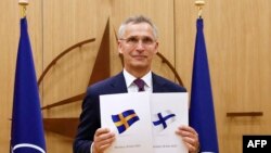 Sekjen NATO Jens Stoltenberg berpose dengan dokumen yang diberikan oleh Dubes Finlandia untuk NATO Klaus Korhonen dan Dubes Swedia untuk NATO Axel Wernhoff dalam upacara untuk menandai aplikasi keanggotaan Swedia dan Finlandia di Brussels, 18 Mei 2022. (JOHANNA GERON/POOL/AFP)