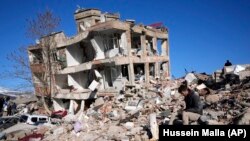 A man sits at his destroyed house in Kahramanmaras, southern Turkey, Wednesday, Feb. 8, 2023. (AP Photo/Hussein Malla)