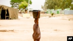 FILE - A child carries a bucket in Yola, Nigeria, April 22, 2016. Droughts, flooding and a shrinking Lake Chad caused in part by climate change is fueling conflict and migration in the region and needs to better addressed, a report said on Jan. 19, 2023.