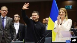 ប្រធានាធិបតី​អ៊ុយក្រែន​លោក Volodymyr Zelenskyy​ (កណ្តាល) លើក​ដៃ​អបអរ នៅ​ក្បែរ​ប្រធាន​សភា​អឺរ៉ុប​លោកស្រី​ Roberta Metsola ដែល​ទះដៃ ក្នុង​អំឡុង​កិច្ចប្រជុំ​កំពូល​មួយ​នៅ​សភា​អឺរ៉ុប​នៅ​ក្រុង​ព្រុចសែល​ ប្រទេស​បែលហ្ស៊ិក កាល​ពី​ថ្ងៃ​ទី​៩ ខែ​កុម្ភៈ ឆ្នាំ​២០២៣។