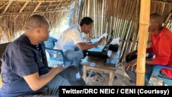 Denis Kadima (1er plan, à g.) le chef de la Commission nationale électorale indépendante de la RDC, assiste à l'enregistrement d'un électeur, le 27 janvier 2023.