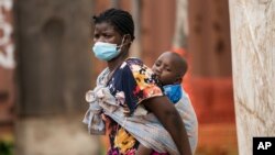 A woman carries her son, who has cholera, at Bwaila Hospital in Lilongwe central Malawi, Wednesday, Jan. 11, 2023. Malawi's health minister says the country's worst cholera outbreak in two decades has killed 750 people so far.