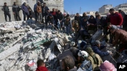 Tim penyelamat dan warga mencari korban gempa di antara puing-puing bangunan yang hancur di kota Harem dekat perbatasan Turki, provinsi Idlib, Suriah (foto: dok). 