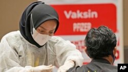 Seorang nakes memberikan suntikan booster vaksin COVID-19 Pfizer kepada seorang pria di pusat vaksinasi di Jakarta, Selasa, 18 Januari 2022. (AP /Dita Alangkara)