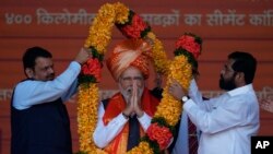 India's western state of Maharashtra Chief Minister Eknath Shinde, right, and his deputy Devendra Fadnavis, left, present a garland to Indian Prime Minister Narendra Modi during a rally in Mumbai, India, Jan. 19, 2023.