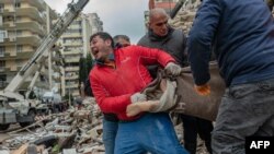 Des sauveteurs transportent une victime trouvée dans les décombres à Adana, en Syrie, le 6 février 2023.