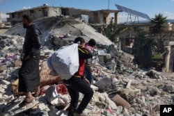 People search through the rubble of collapsed buildings where a newborn girl was found in the town of Jinderis, Aleppo province, Syria, Tuesday, Feb. 7, 2023. (AP Photo/Ghaith Alsayed)