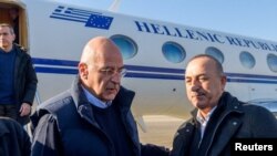 Greek Foreign Minister Nikos Dendias is welcomed by his Turkish counterpart Mevlut Cavusoglu, following the deadly earthquake, in Adana, Turkey, Feb. 12, 2023. (Greek Foreign Ministry/Handout via Reuters) 