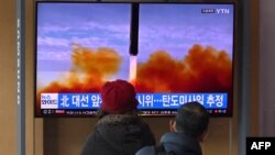 People watch a television screen showing a news broadcast with file footage of a North Korean missile test, at a railway station in Seoul, South Korea, on March 5, 2022.
