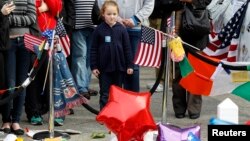 A young girl looks at a memorial to the victims of the Boston Marathon bombings on Boylston Street near the scene of the blasts in Boston, Massachusetts, Apr. 20, 2013. 