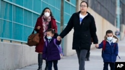 Children and their caregivers arrive for school in New York, Monday, March 7, 2022. (AP Photo/Seth Wenig)