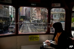 Seorang perempuan mengenakan masker saat naik trem di Hong Kong, Selasa, 8 Maret 2022. (Foto AP/Kin Cheung)