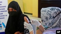 A Somalian refugee receives a shot of the Pfizer COVID-19 vaccine during a mass vaccination campaign for refugees in North Sumatra, Indonesia, Dec. 8, 2021.
