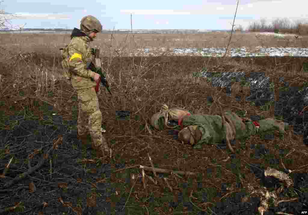 A serviceman of the Ukrainian Military Forces examines a body following fighting against Russian troops and Russia-backed separatists near the village of Zolote, Lugansk region, March 6, 2022.