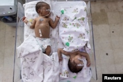 FILE - Babies sleep in a shared bed at the maternity unit at the Indira Gandhi hospital in Kabul, Afghanistan, Oct. 24, 2021.